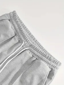 Dettaglio pantaloncini grigi a trama nido d'ape con vita elastica e coulisse bianca