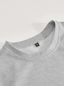 Dettaglio ravvicinato di una maglia grigia in nido d'ape con etichetta della taglia M