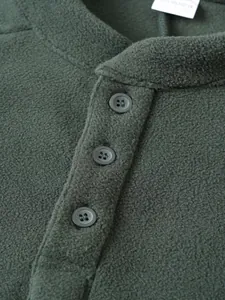 Close-up van donkergroen fleece sweatshirt met opstaande kraag en drieknoopssluiting