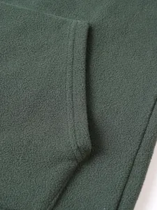 Detailopname van donkergroene fleecestof met stikseldetails en textuurkwaliteit.