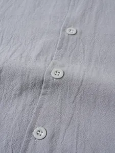 Vue détaillée de la texture du tissu en lin respirant et des boutons de la chemise homme
