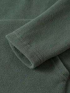 Detailopname van de mouw van een donkergroene fleece trui met een zachte textuur.