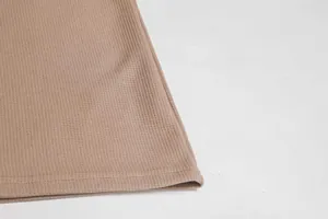 Nahaufnahme der Waffelstrick-Struktur und des Saums eines braunen Herren-Shirts.