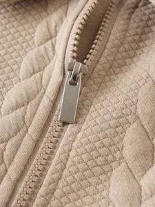 Détail en gros plan d'une fermeture éclair et tissu matelassé sur un sweat beige homme.
