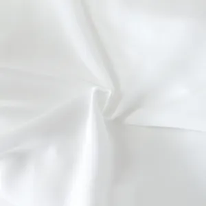 Hoogwaardig wit stofdetail met zachte textuur en spiraalvormige plooien van een jurk.