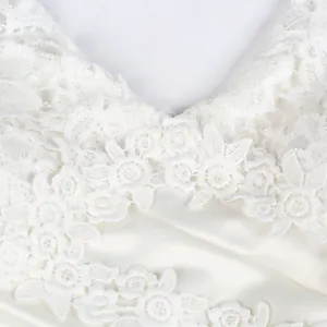 Close-up of delicate white floral lace and satin fabric on elegant bridal dress