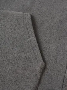 Detailopname van zachte grijze fleece stof en de strakke zakstiksels op de winterhoodie voor heren