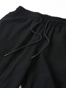 Gros plan détaillé d'un pantalon en lin noir avec taille élastique à cordon.