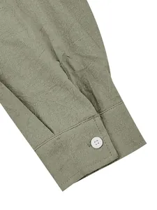 Close-up detail of cotton-linen shirt cuff with white button in sage green finish