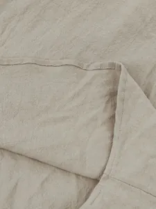 Detail macro view showing the natural cotton linen fabric texture and hem stitching of a shirt.