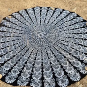Vue détaillée d'une serviette de plage ronde mandala noir et blanc avec motif paon sur sable.