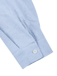 Macro view of light blue cotton-linen shirt cuff showing fabric texture and button detail