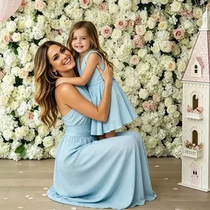 Madre e hija posan con vestidos formales azul claro a juego ante una pared de flores