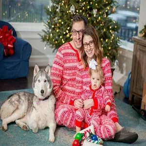 Gelukkige familie in bijpassende rood-witte kerstpyjama's bij de kerstboom thuis