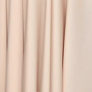 Macro view of high-quality apricot fabric showing fine texture and elegant drape details.