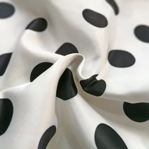 Detailed close-up showing the smooth satin texture and black polka dot pattern of the fabric