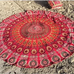 Serviette de plage ronde mandala rouge bohème avec motif de paon sur le sable fin.