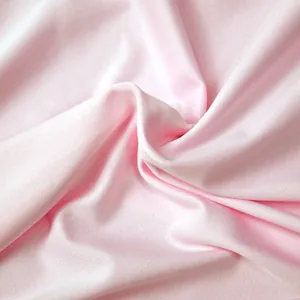Détail en gros plan montrant la texture douce du tissu de robe de maternité rose