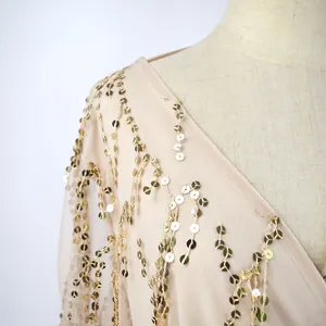 Detailed view of shimmering gold sequin tassels on champagne mesh long sleeve dress