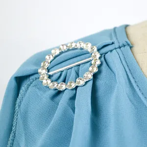 Primo piano di una fibbia rotonda con strass su tessuto di chiffon blu di un abito