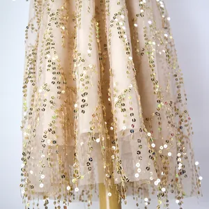 Close-up of elegant champagne tulle dress with vertical gold sequin fringe details