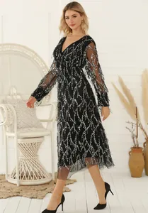 Detail of black V-neck sequin dress with tassels and mesh long sleeves for evening wear.