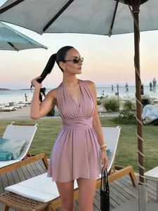 Mini-robe portefeuille mauve à décolleté en V et jupe plissée portée à la plage