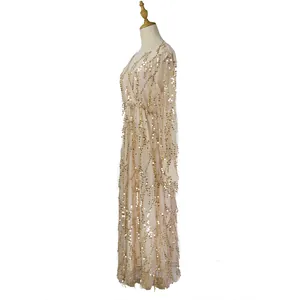 Side view detail of a long-sleeved beige dress with gold sequins and fringe tassels