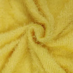 Close-up detail of soft yellow plush fabric texture for long-sleeve knit dresses.