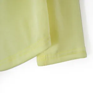 Primer plano de la doble costura en el dobladillo de una camiseta de manga larga amarilla