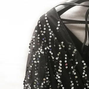Close-up detail of shimmering silver sequins on black mesh long sleeve evening dress