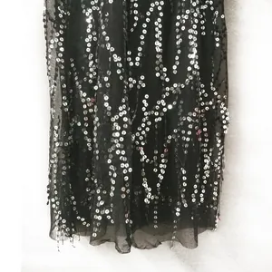 Macro view of shimmering silver sequins and delicate mesh hem on black evening maxi dress