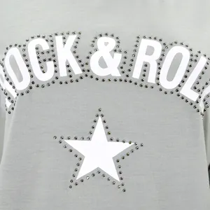 Primer plano detallado del estampado ROCK & ROLL y estrella con pedrería en sudadera gris