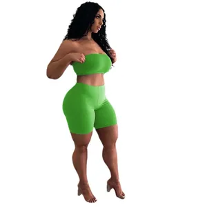 Completo sportivo verde due pezzi con top a fascia e pantaloncini da fitness aderenti.