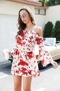 Full view of red and white tie-dye mini dress on a model in a sunny outdoor setting.
