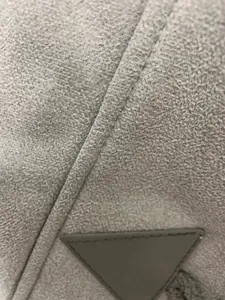 Detail shot showing the soft grey suede texture and precise stitching of a winter coat