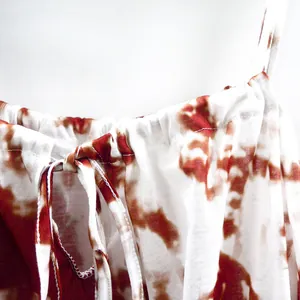 Detailed macro shot of a red tie-dye printed camisole dress featuring a drawstring neckline
