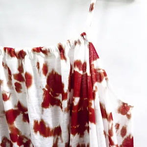 Close-up detail of red tie-dye print and gathered neckline on a summer cami dress.