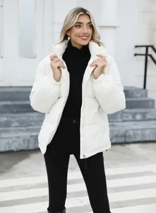 Elegant women's white puffer jacket paired with a black turtleneck in outdoor setting