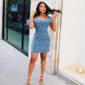 Elegant detail view of an off-shoulder denim bodycon dress featuring stylish blue feather trim
