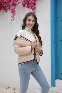 Model trägt eine leichte beige Steppjacke mit braunem Besatz in einer Streetstyle-Umgebung
