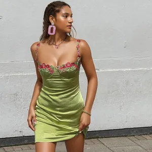 Vue détaillée de la mini-robe en satin vert avec broderie florale exquise sur le buste.