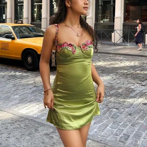 Vue détaillée d'une mini robe en satin vert avec une broderie florale exquise sur le buste.