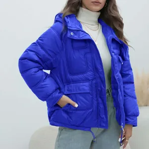 Detail of bright blue women's thickened winter puffer jacket with hood and pockets.