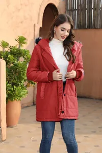 Stylish woman wearing a red hooded mid-length parka jacket in an outdoor setting