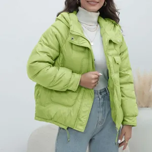 Fashion model wearing a bright lime green thick hooded puffer jacket in a minimalist studio.