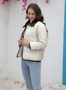 Model trägt eine schicke cremefarbene Steppjacke mit schwarzem Besatz und Cordkragen.