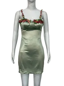Détail de la robe courte en satin vert sauge avec broderies florales sur les bretelles