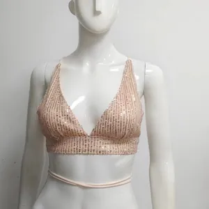 Dettaglio di un top bikini scintillante con paillettes oro rosa e lacci intrecciati.