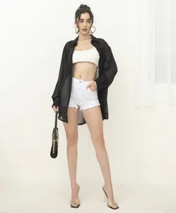 Full body look of the black sheer sequined shirt paired with white denim fashion items